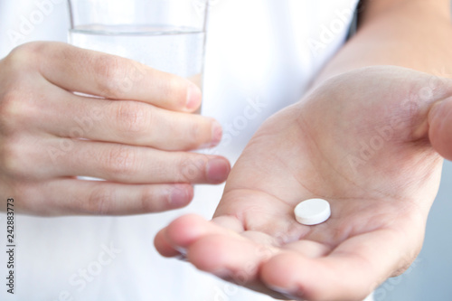 white pill and a glass of water in man hands. health concept 