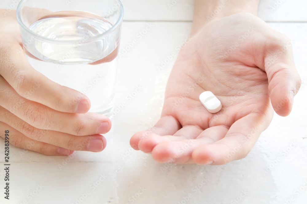 Naklejka premium white pill and a glass of water in man hands. health concept 