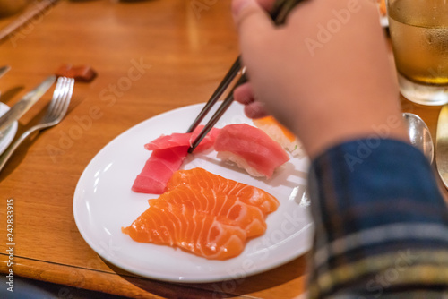 Woman hand using chopsticks to eat Japanese Sashami photo