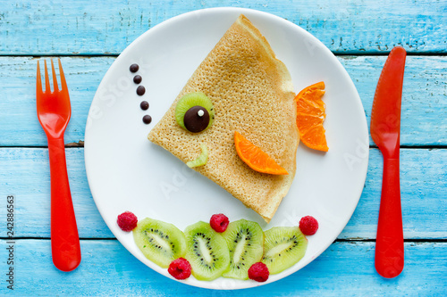 Funny pancakes with fruits shaped fish for kids breakfast