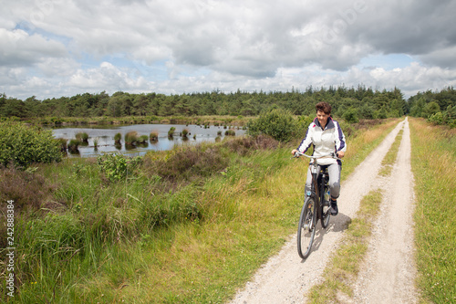 Biking woman in Dutch national park with forest and wetlands