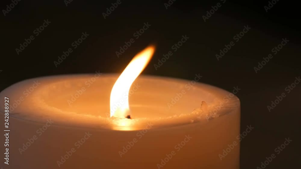 Large white burning candle in the dark. Flame of candle in the night close up view Large white burning candle in the dark. Flame of candle in the night close up view