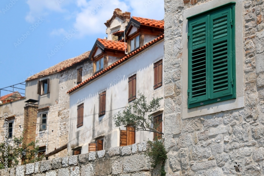 Traditional Mediterranean architecture in Sibenik, Croatia. Stone walls and woode windows with olive plant in the garden. Sibenik is popular summe travel destination.