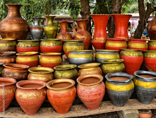 Clay pots stacked for sale on African roads. Pottery making place. Local craft market in Africa. Unique handmade colorful ceramic pots. Craftsmanship. African style.