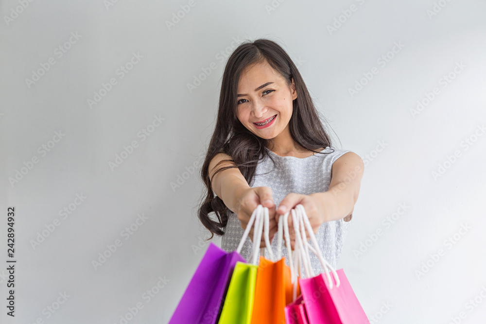 Women submit shopping bags to you. Young shopper. Shopping woman smiling.  Beautiful Asian girl. Photos | Adobe Stock