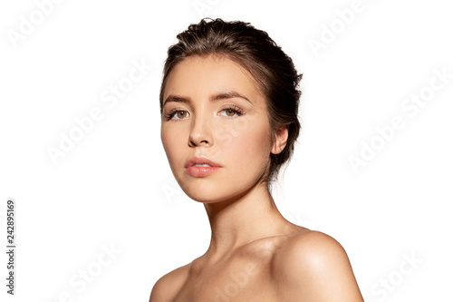 Portrait of pretty young woman with serious face. Adorable female with nude natural makeup looking at camera. Studio photo shoot. Isolated on white background