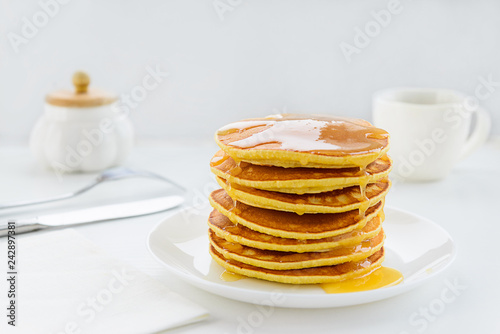 Pancakes with honey on a white wooden table