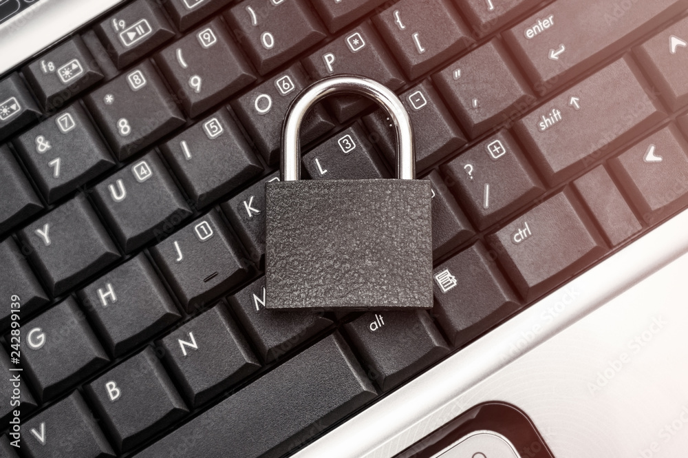 Padlock on the laptop keyboard. Top view. Toned image. Padlock on the laptop keyboard. Top view. Toned image.