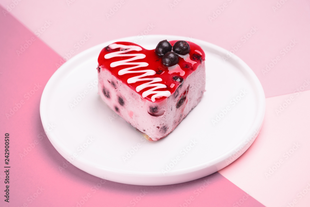 delicious dessert in the shape of a heart, currant cake, cream souffle, decorated with berries and poured jelly on a white plate. On a colored purple background delicious dessert in the shape of a heart, currant cake, cream souffle, decorated with berries and poured jelly on a white plate. On a colored purple background