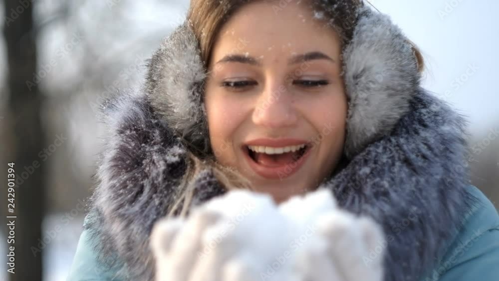 beautiful young woman holding snow in her hands and blowing on it beautiful young woman holding snow in her hands and blowing on it