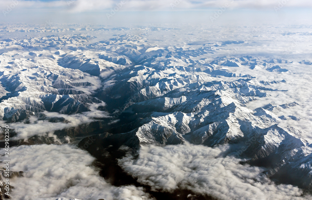Range of snow capped Himalaya mountains with white clouds, shot from airplane - Tibet