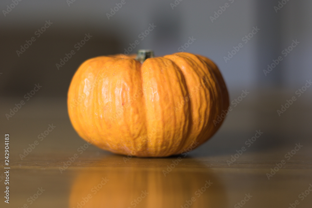 Orange pumpkin is on a wooden table and is reflected in it. Concept: autumn color and minimalism. Orange pumpkin is on a wooden table and is reflected in it. Concept: autumn color and minimalism.