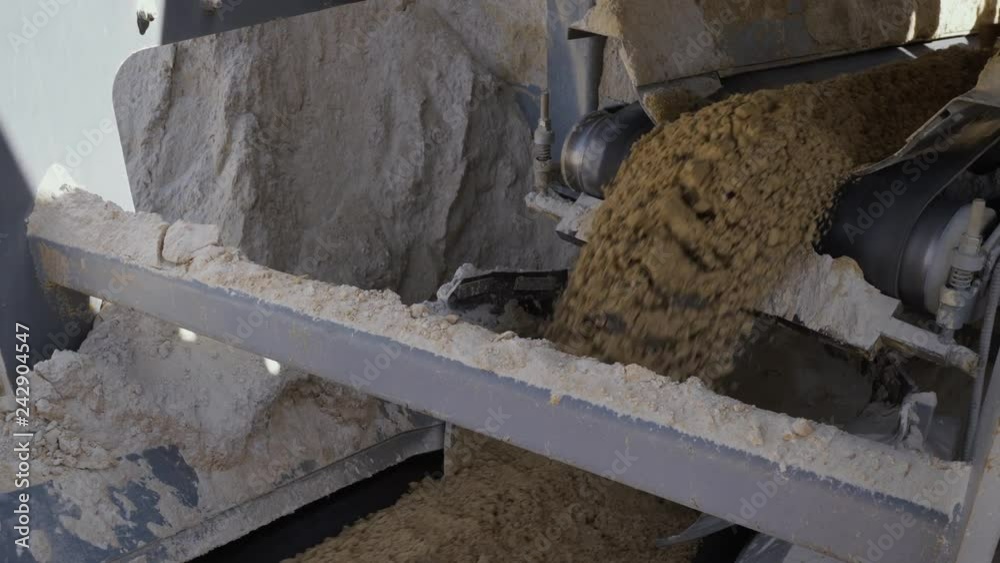 Processing of sand and ground. Machines working and conveyor line transporting sand. Open pit. Close up Processing of sand and ground. Machines working and conveyor line transporting sand. Open pit. Close up