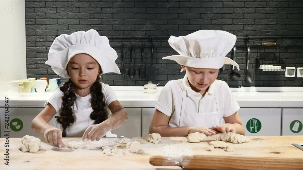Adorable schoolkids playing with dough and flour in kitchen. Young chefs work together. 4k Adorable schoolkids playing with dough and flour in kitchen. Young chefs work together. 4k