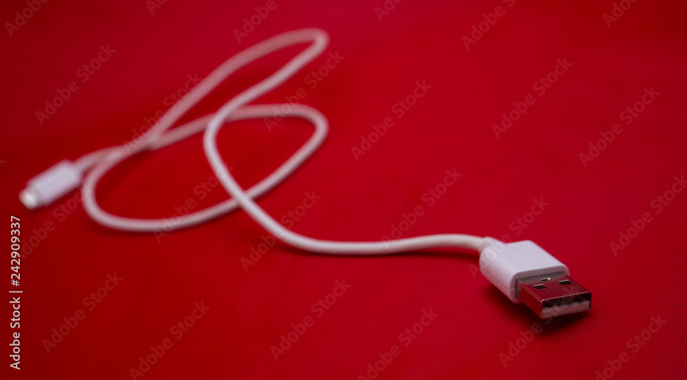 White USB cable in red background. Horizontal photo. White USB cable in red background. Horizontal photo.