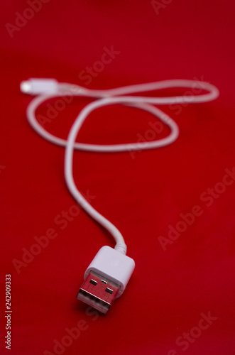 White USB cable in red background. Vertical photography