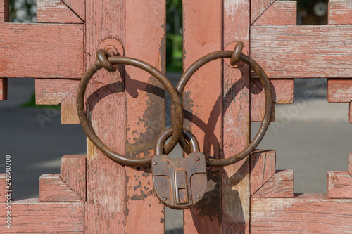 Obraz na plátně Padlock on vintage wooden gates. Rusty and closed locking system.