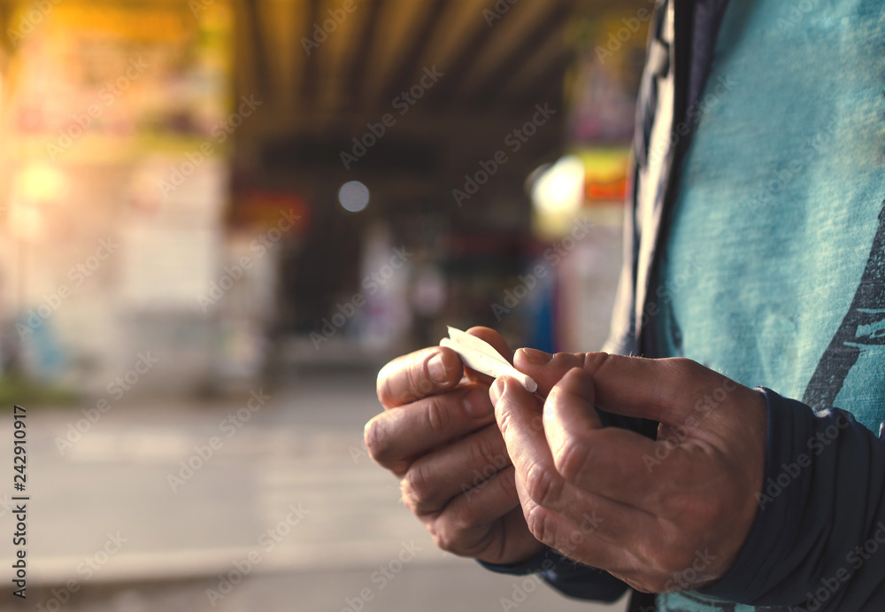 A men rolls cigarette with hand rolling tobacco in the city