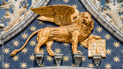 Golden winged lion with parchment as roof decoration of Basilica San Marco in Venice, Italy, summer time