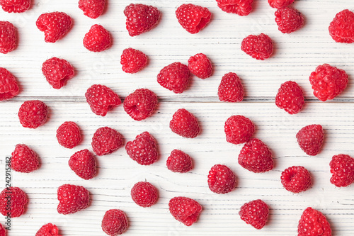Tabletop view - raspberries scattered on white boards.