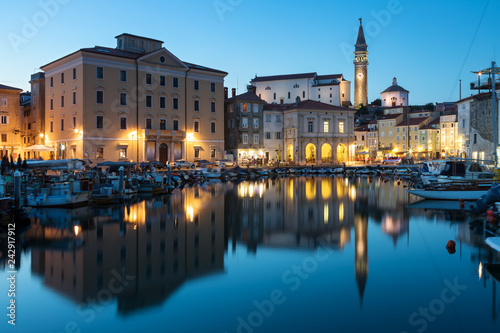 Night view of old city Piran in Slovenia. Beautiful cityscape through marina to Tartini Square.