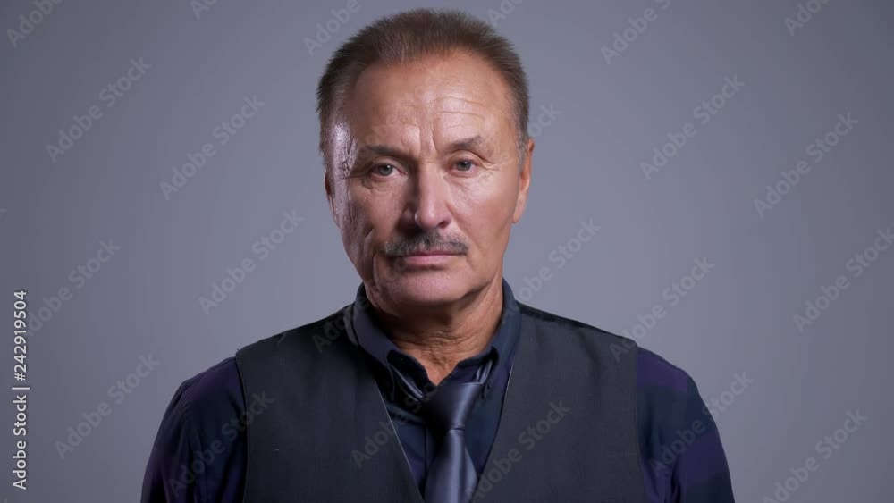 Closeup portrait of eldery caucasian man looking straight at camera with neutral facial expression