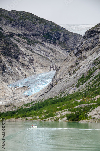 Distance view of the Nigardsbreen glacier with boat on the lake in the foreground