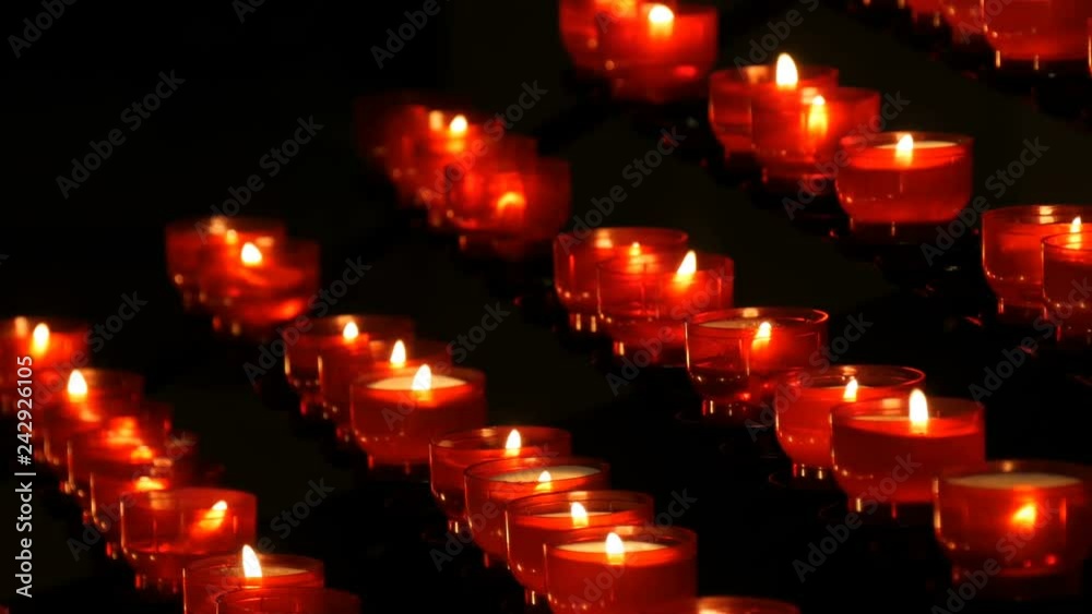 Row of christian prayer red round votive candles burn in the dark. Prayer lighting Sacrificial Candles. Burning memorial candles in the Catholic church. Celebrating christmas in Cathedral Row of christian prayer red round votive candles burn in the dark. Prayer lighting Sacrificial Candles. Burning memorial candles in the Catholic church. Celebrating christmas in Cathedral