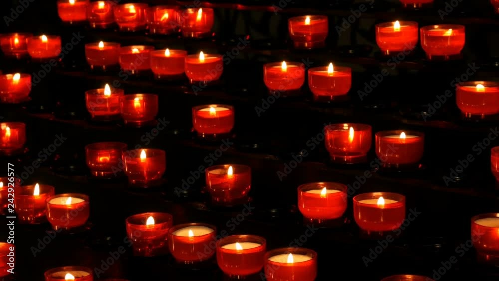 Row of christian prayer red round votive candles burn in the dark. Prayer lighting Sacrificial Candles. Burning memorial candles in the Catholic church. Celebrating christmas in Cathedral Row of christian prayer red round votive candles burn in the dark. Prayer lighting Sacrificial Candles. Burning memorial candles in the Catholic church. Celebrating christmas in Cathedral