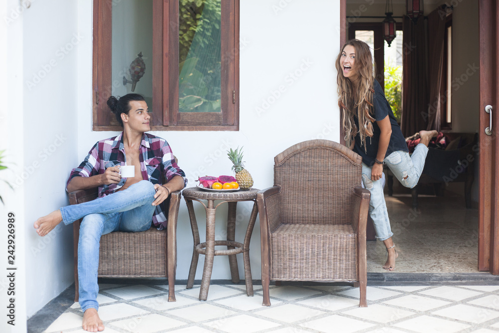 Young couple is outside of house are having fruit breakfast and laughing Young couple is outside of house are having fruit breakfast and laughing