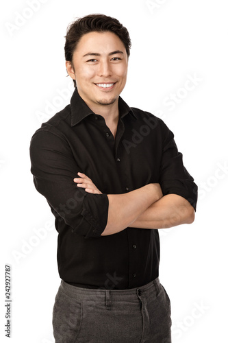 Attractive man in a black shirt and grey pants, standing with a big smile against a white background,