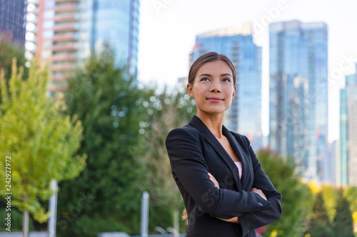 Asian businesswoman. Happy business woman portrait pensive looking up contemplative of her career. City job employment. Chinese professional in black suit confident with crossed arms.