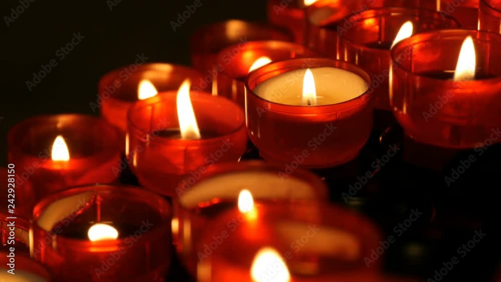 Row of christian prayer red round votive candles burn in the dark. Prayer lighting Sacrificial Candles close up view. Burning memorial candles in Catholic church. Celebrating christmas in Cathedral Row of christian prayer red round votive candles burn in the dark. Prayer lighting Sacrificial Candles close up view. Burning memorial candles in Catholic church. Celebrating christmas in Cathedral