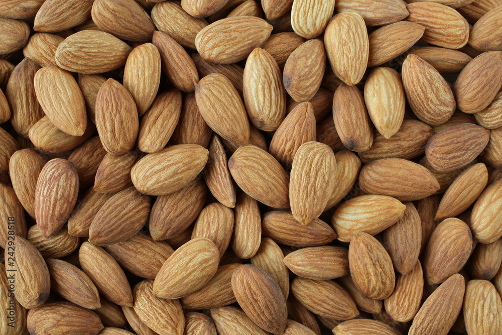 Background of big raw peeled almonds situated arbitrarily Background of big raw peeled almonds situated arbitrarily