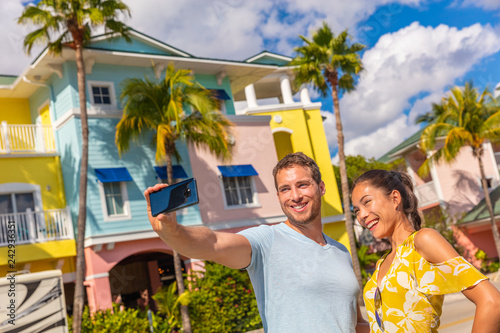 Tableau sur toile Selfie photo couple tourists taking picture with smart phone in Fort Myers, Florida at colorful wood beach cottages