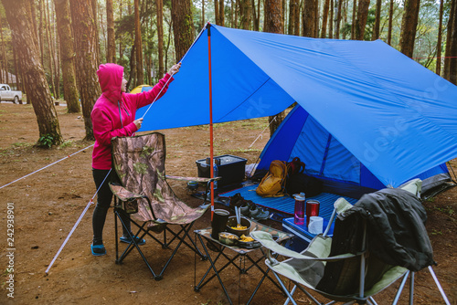 Women Nature tourism, camping in the middle of the pine forest. Adjusting and pulling the tent rope.