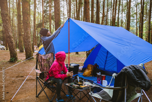 young asian couple of happy enjoying Camping in the pine forest Sit and eat food at the Camping page in the midst of nature.