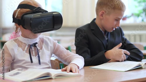 Schoolgirl use of VR goggles in lessons. Virtual reality technology for children in a modern school. photo