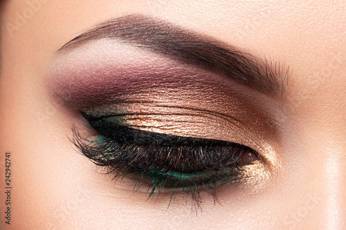 Close up of beautiful woman eye with multicolored smokey eyes makeup. Modern fashion make up. Studio shot photo