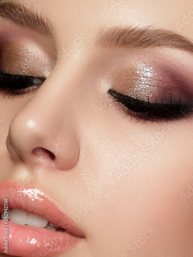 Closeup portrait of young beautiful woman with evening make up. Pink and gold multicolored smokey eyes. Luxury skincare and modern fashion makeup concept. Studio shot. Extreme closeup, partial face