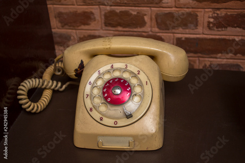 old beige vintage dial telephone on a brown table