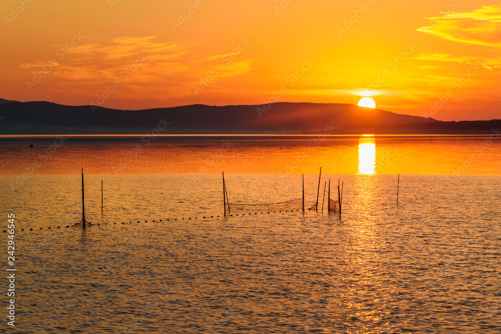View of sunrise in lagoon Orbetello on peninsula Argentario. Italy View of sunrise in lagoon Orbetello on peninsula Argentario. Italy