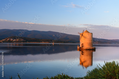 Old Spanish windmill in lagoon Orbetello on peninsula Argentario at sunise. Italy photo