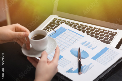 Businesswoman holding mug of coffee and acquainted with diagrams