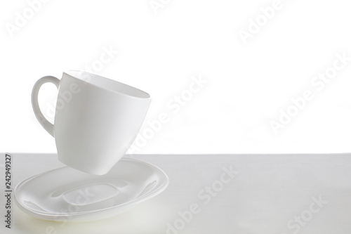 White cup with saucer in a jump on a white background. Jumping cup. Flying dishes on a white background.White dishes on a white background