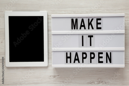 Lightbox with text 'Make it happen', tablet with blank screen on a white wooden background, top view. From above, flat lay, overhead.