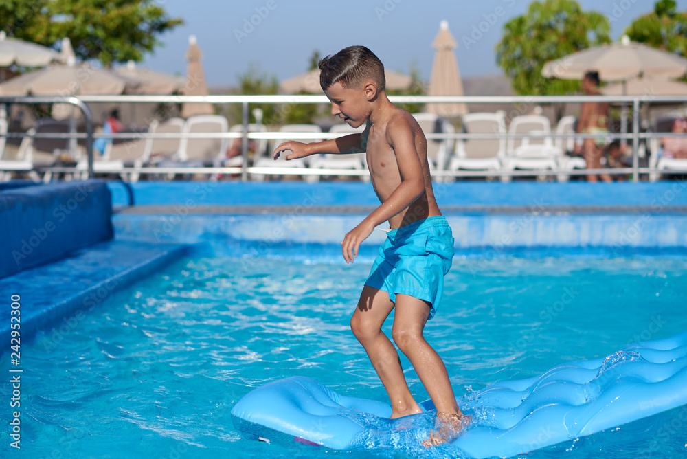 Smiling Caucasian boy having fun in swimming pool at resort on family vacation.