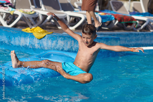 Caucasian boy having fun making fantastic jump into swimming pool at resort. He has wide open arms and crossed legs.