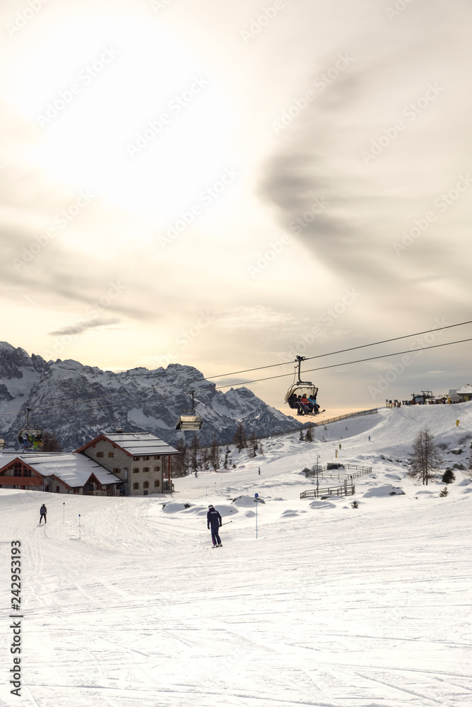 ski slopes with skiers at sunset. Trentino, Italy