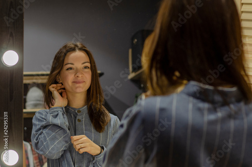 Portrait of a young girl looking in the mirror while choosing clothes in a stylish boutique